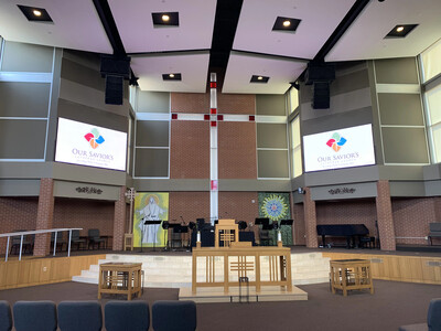 Two display screens above the front of a church sanctuary